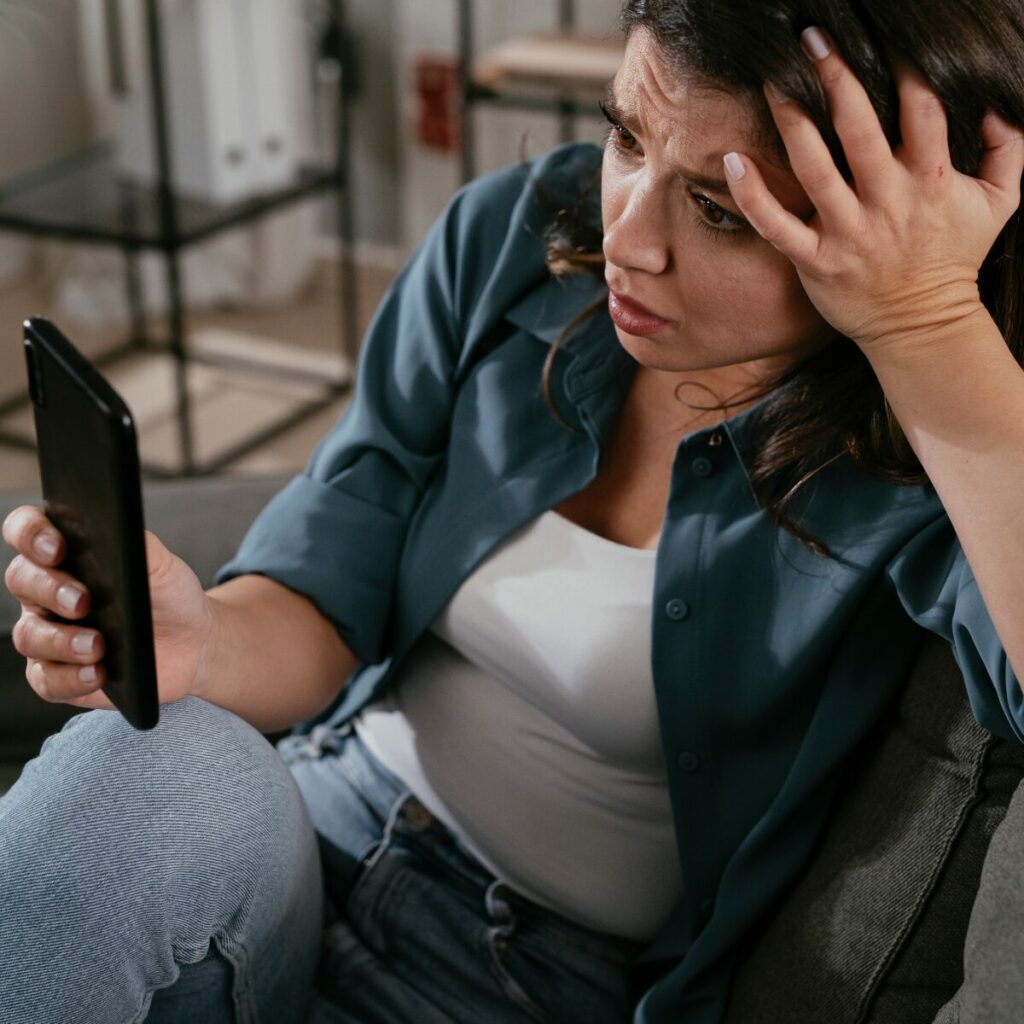 Come gestire la rabbia: ragazza che guarda il cellulare spazientita.