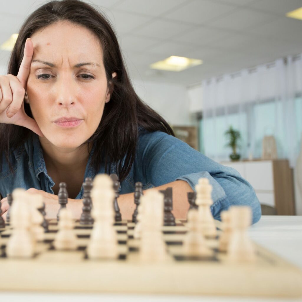 Come gestire la rabbia con il problem solving: ragazza che pensa davanti a una scacchiera.